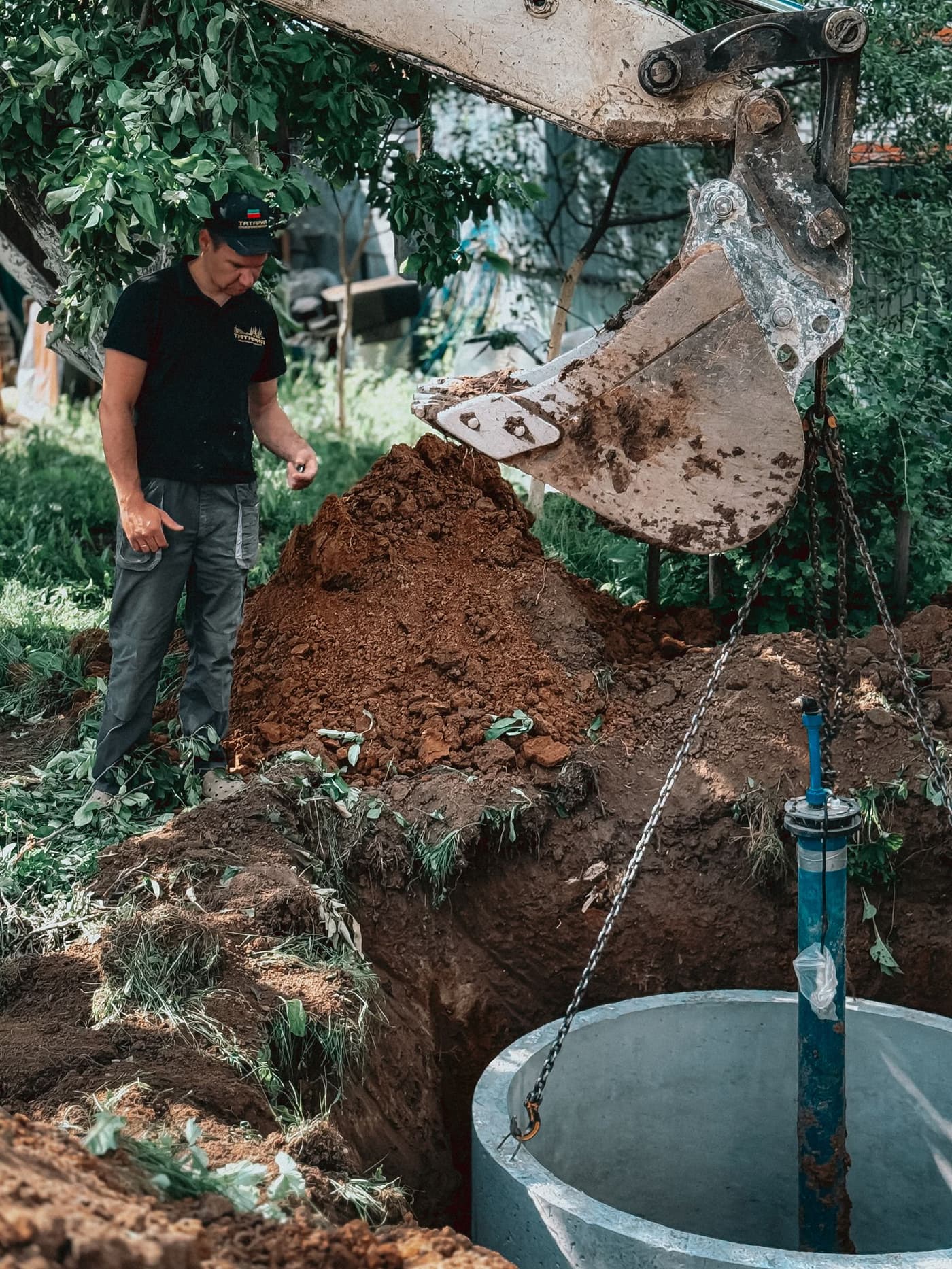 An excavator setting a concrete septic tank at an Albany-area home site